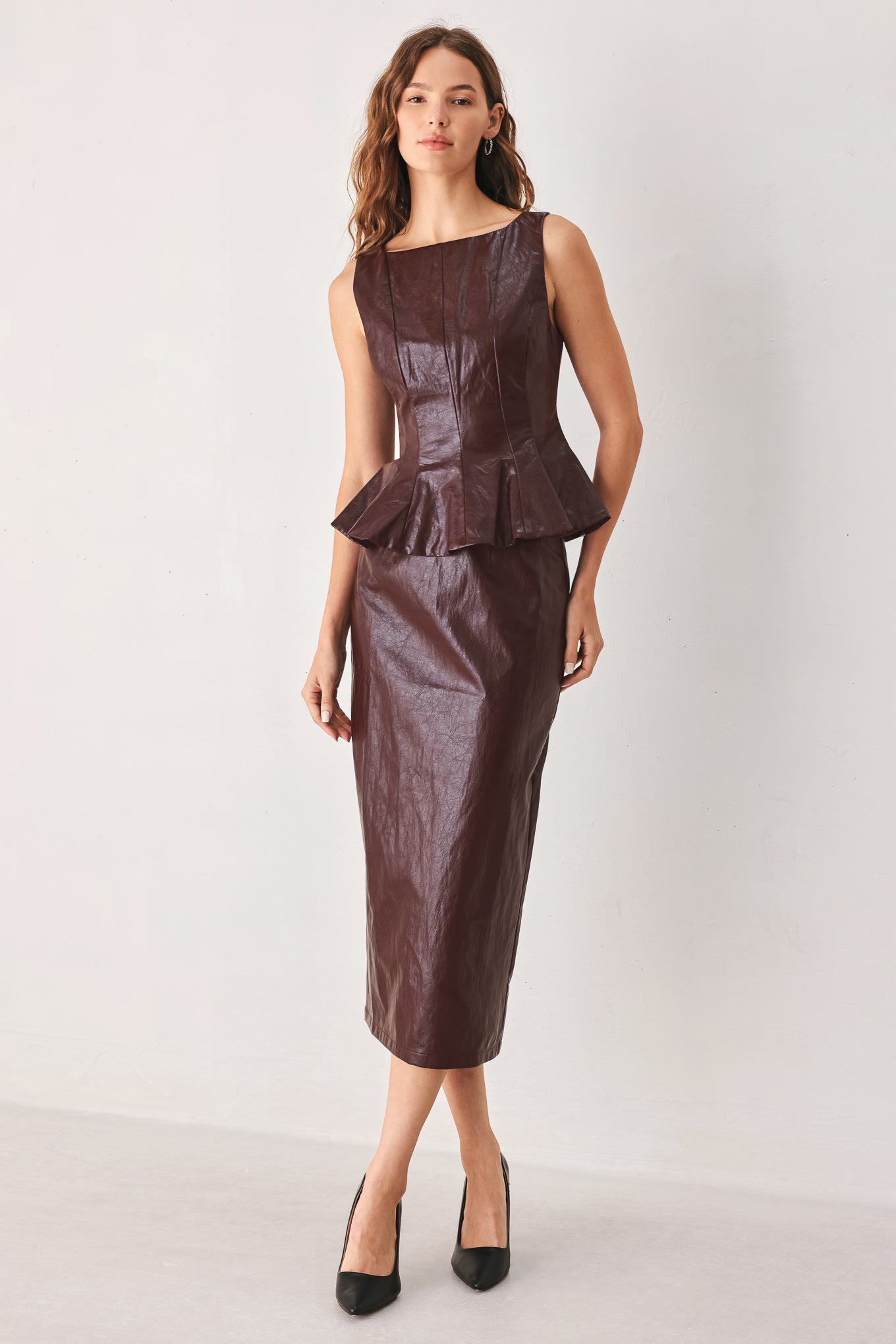 A woman wearing a sleeveless burgundy faux-leather peplum top | FREEMARKET