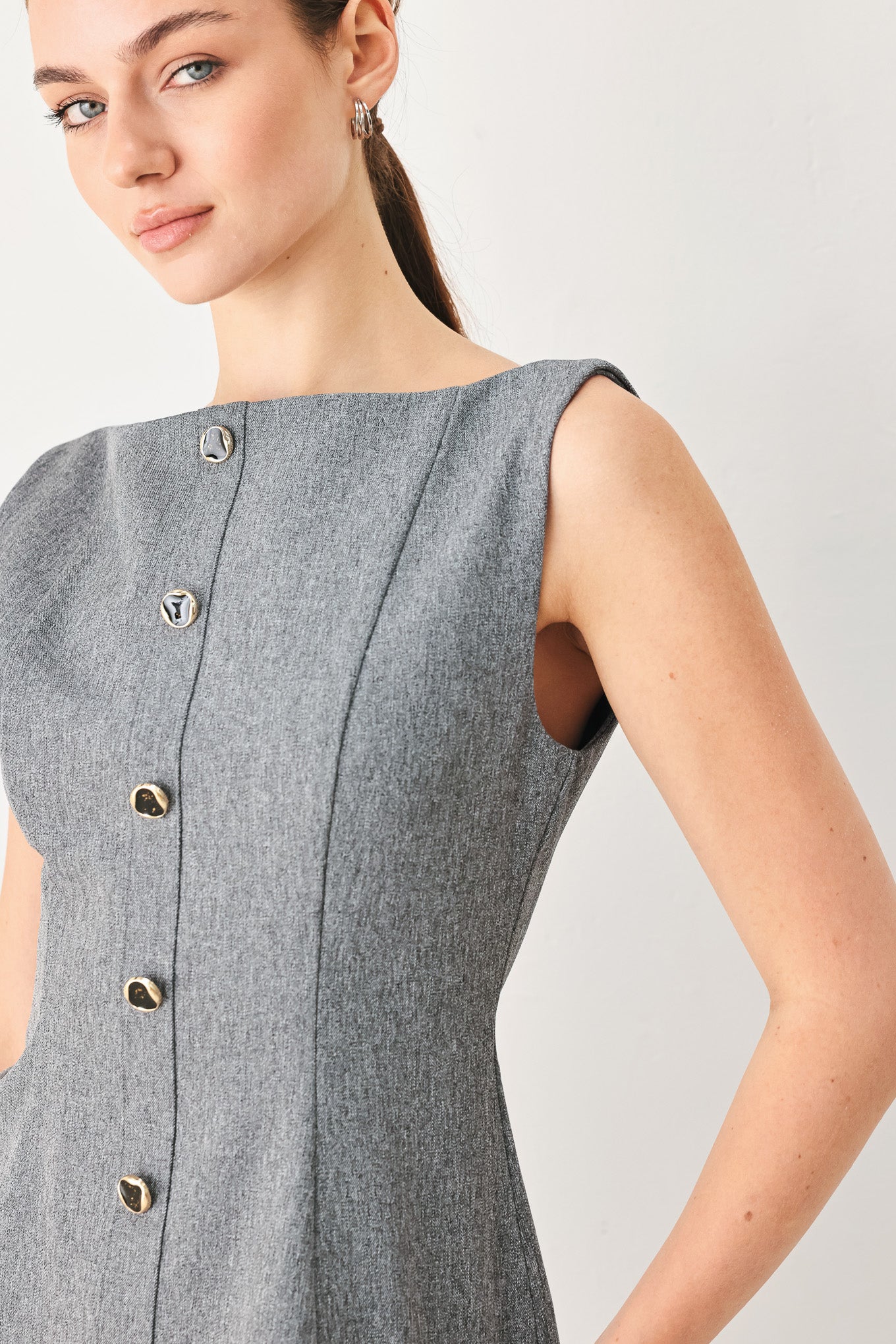 A woman wearing a gray sleeveless button-front top featuring wide neckline | FREEMARKET