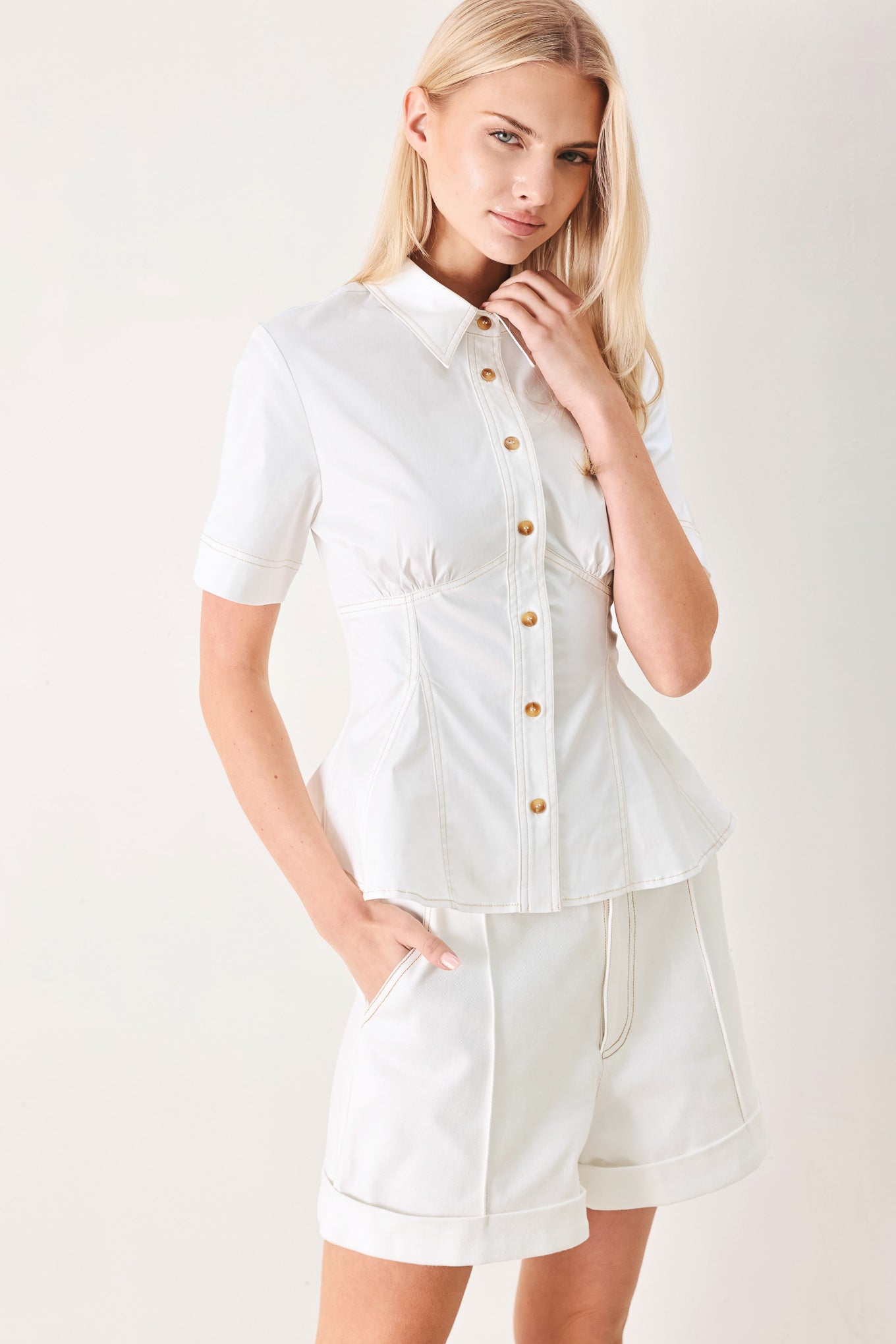 Woman wearing a white  top with front button closure, short sleeve and peplum | FREEMARKET
