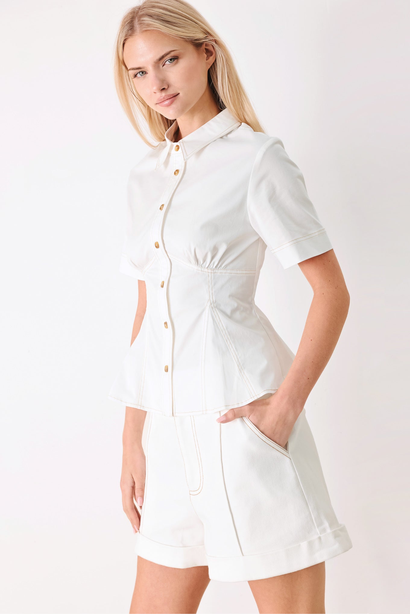 Woman wearing a white  top with front button closure, short sleeve and peplum | FREEMARKET