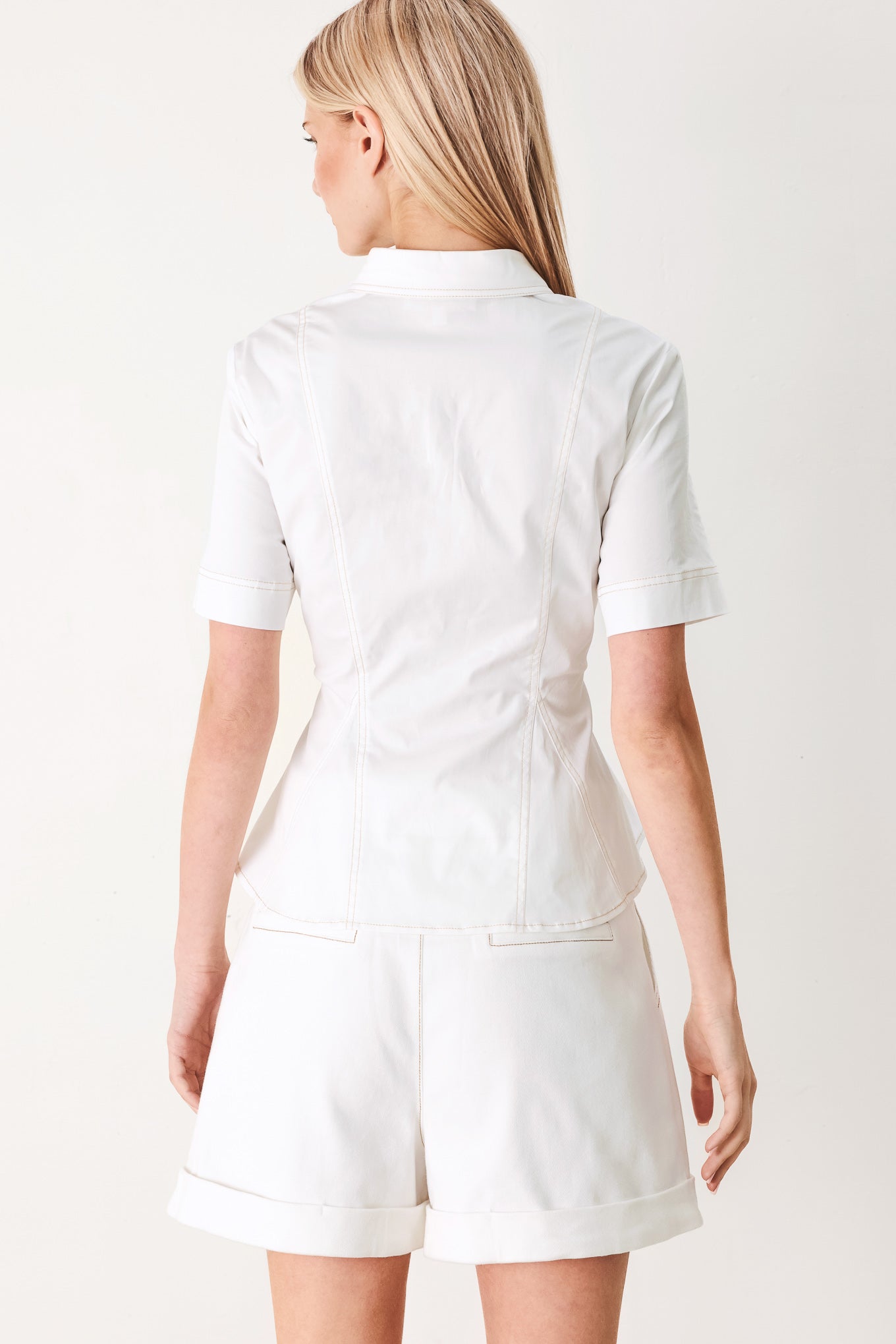 Woman wearing a white  top with front button closure, short sleeve and peplum | FREEMARKET