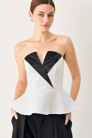 Woman wearing a black and white strapless top with a peplum effect | FREEMARKET