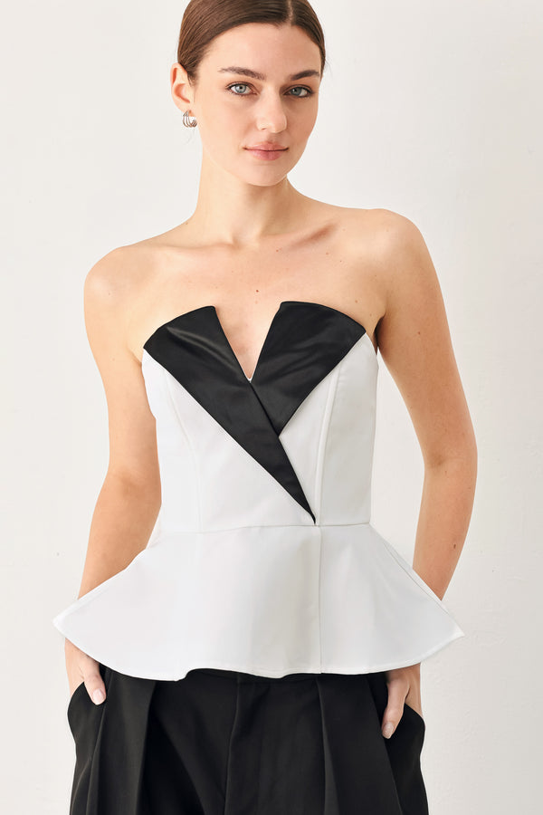 Woman wearing a black and white strapless top with a peplum effect | FREEMARKET