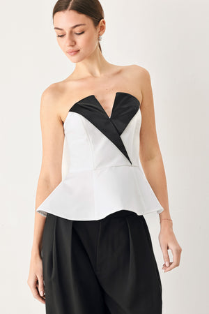 Woman wearing a black and white strapless top with a peplum effect | FREEMARKET
