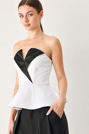 Woman wearing a black and white strapless top with a peplum effect | FREEMARKET