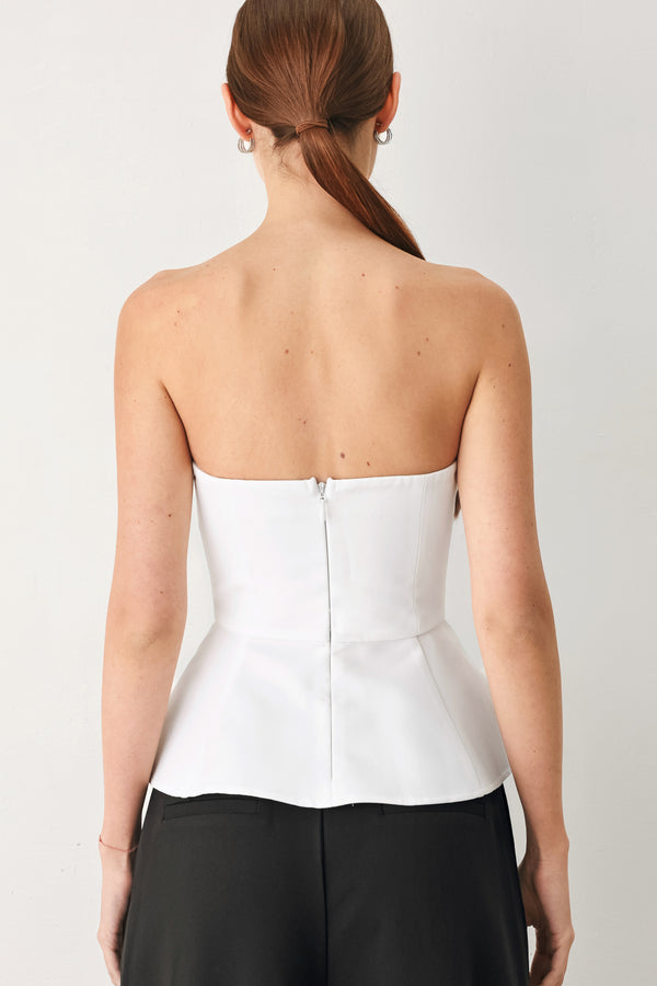 Woman wearing a black and white strapless top with a peplum effect | FREEMARKET