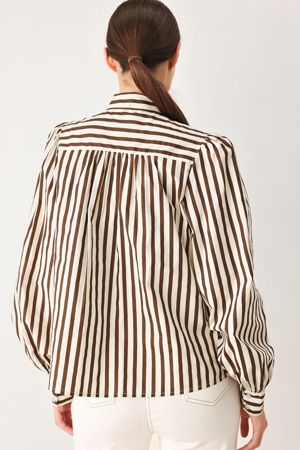 A woman wearing a brown and beige vertically striped long-sleeve blouse with a large bow at the collar | FREEMARKET