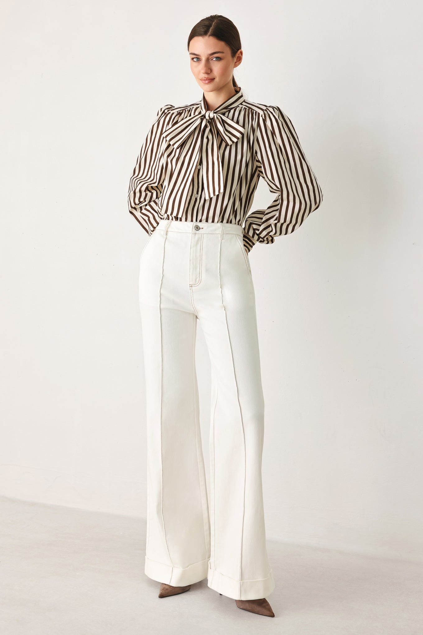 A woman wearing a brown and beige vertically striped long-sleeve blouse with a large bow at the collar | FREEMARKET
