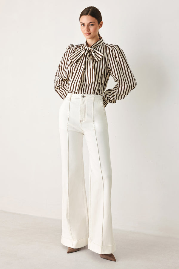 A woman wearing a brown and beige vertically striped long-sleeve blouse with a large bow at the collar | FREEMARKET