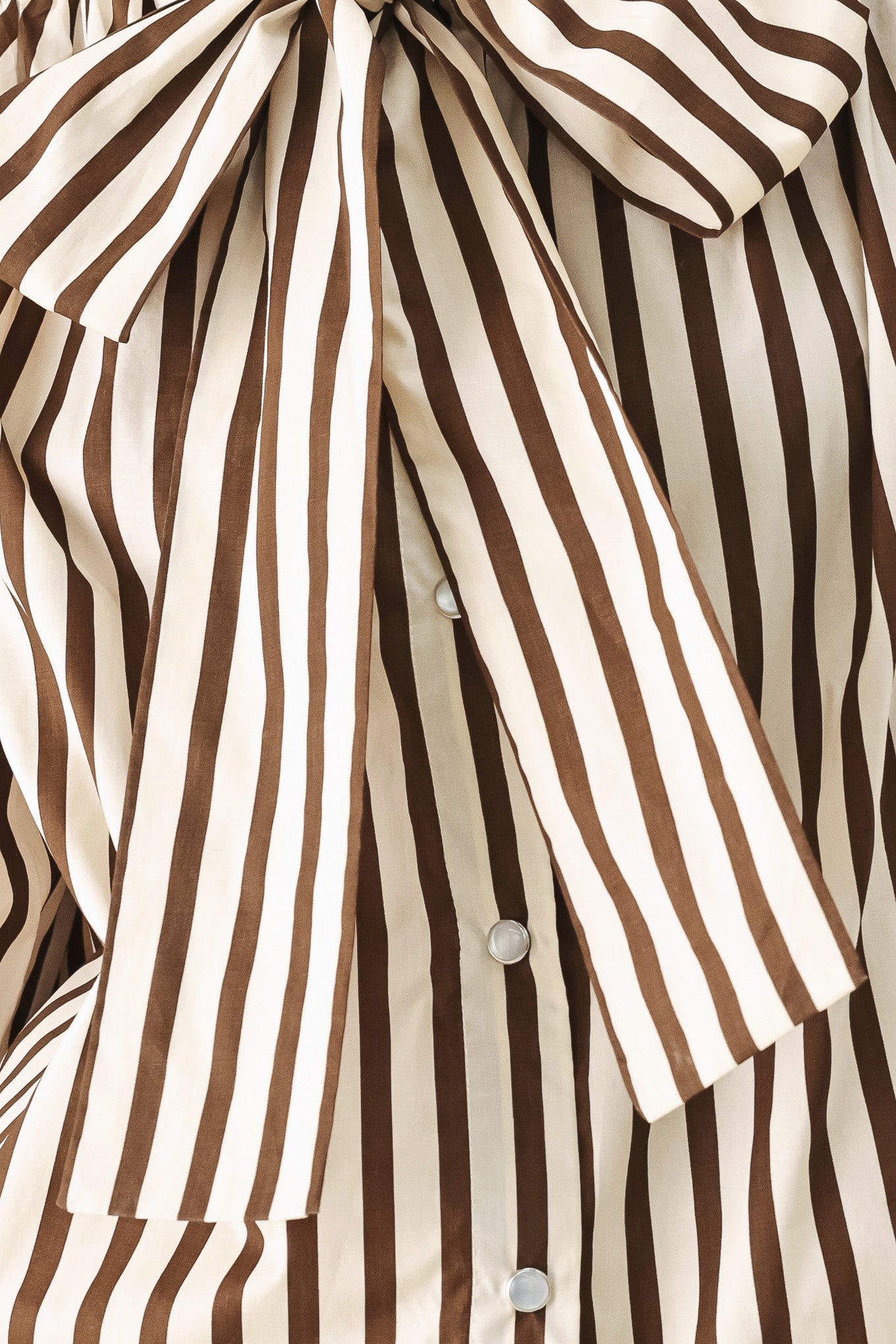 A woman wearing a brown and beige vertically striped long-sleeve blouse with a large bow at the collar | FREEMARKET