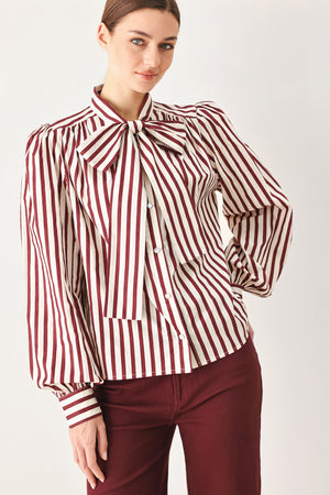 A woman wearing a burgundy and beige vertically striped long-sleeve blouse with a large bow at the collar | FREEMARKET