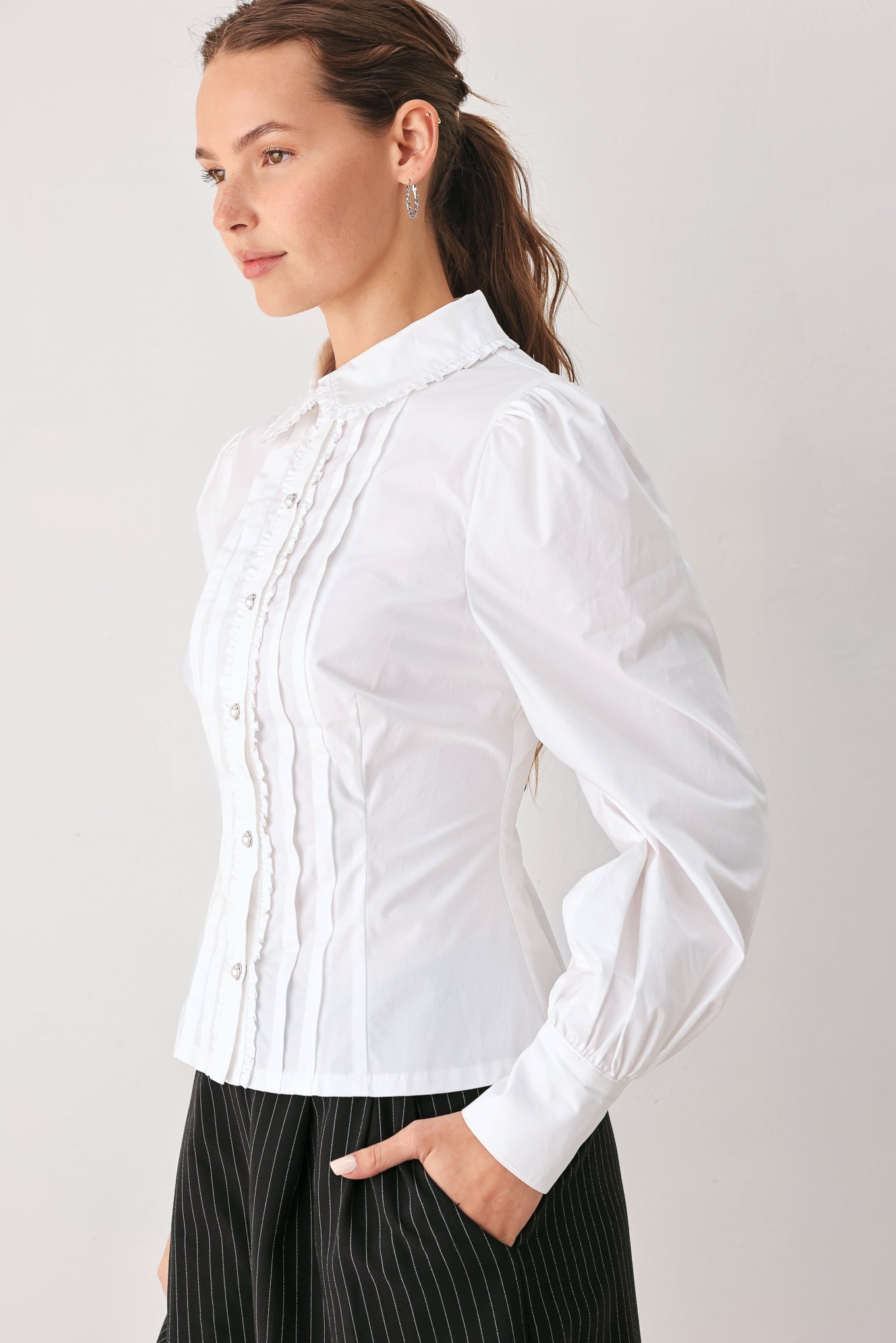 A woman wearing a white long-sleeve blouse with a high collar, decorative front pleats, and puffed shoulders | FREEMARKET