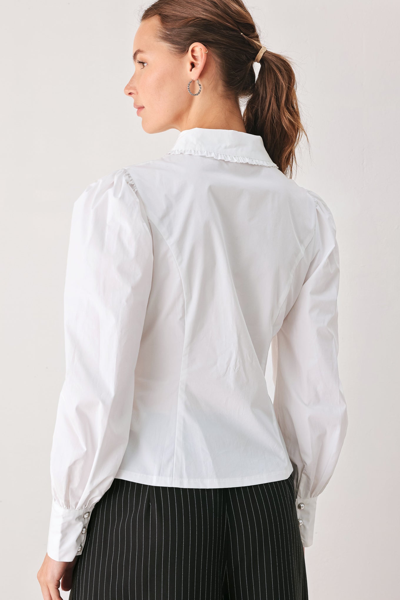 A woman wearing a white long-sleeve blouse with a high collar, decorative front pleats, and puffed shoulders | FREEMARKET