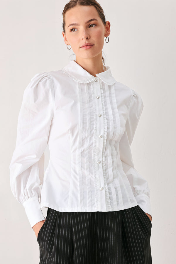 A woman wearing a white long-sleeve blouse with a high collar, decorative front pleats, and puffed shoulders | FREEMARKET