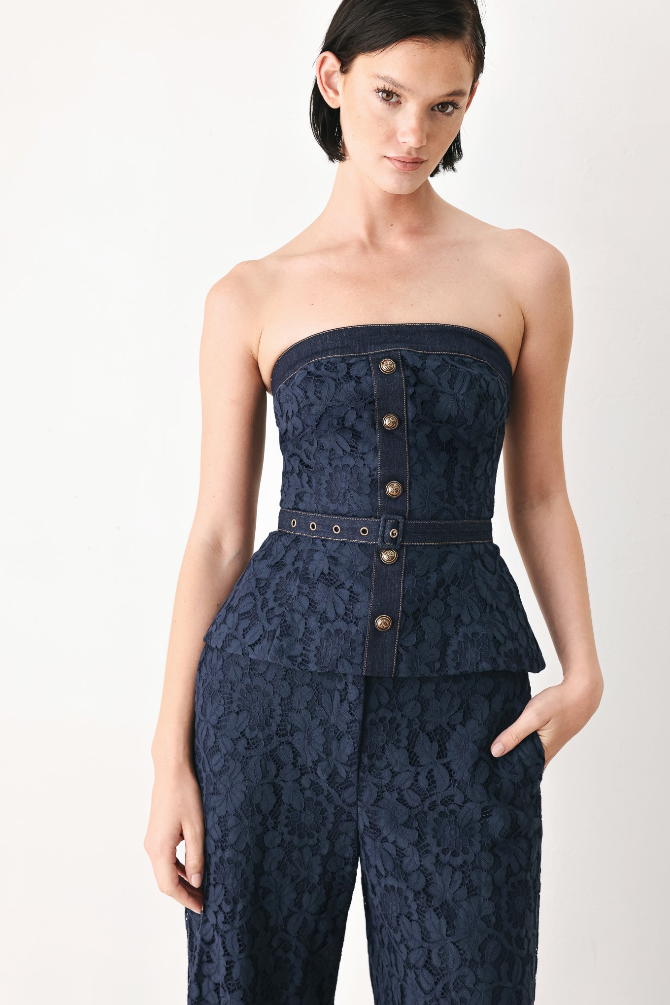 A woman wearing a strapless dark navy blue textured dress with a buttoned waist and a matching belt | FREEMARKET