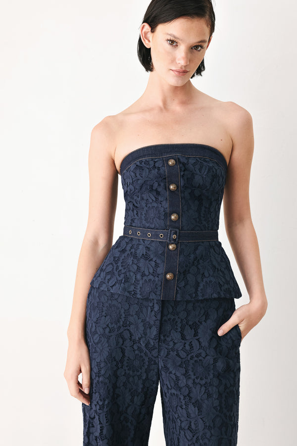 A woman wearing a strapless dark navy blue textured dress with a buttoned waist and a matching belt | FREEMARKET