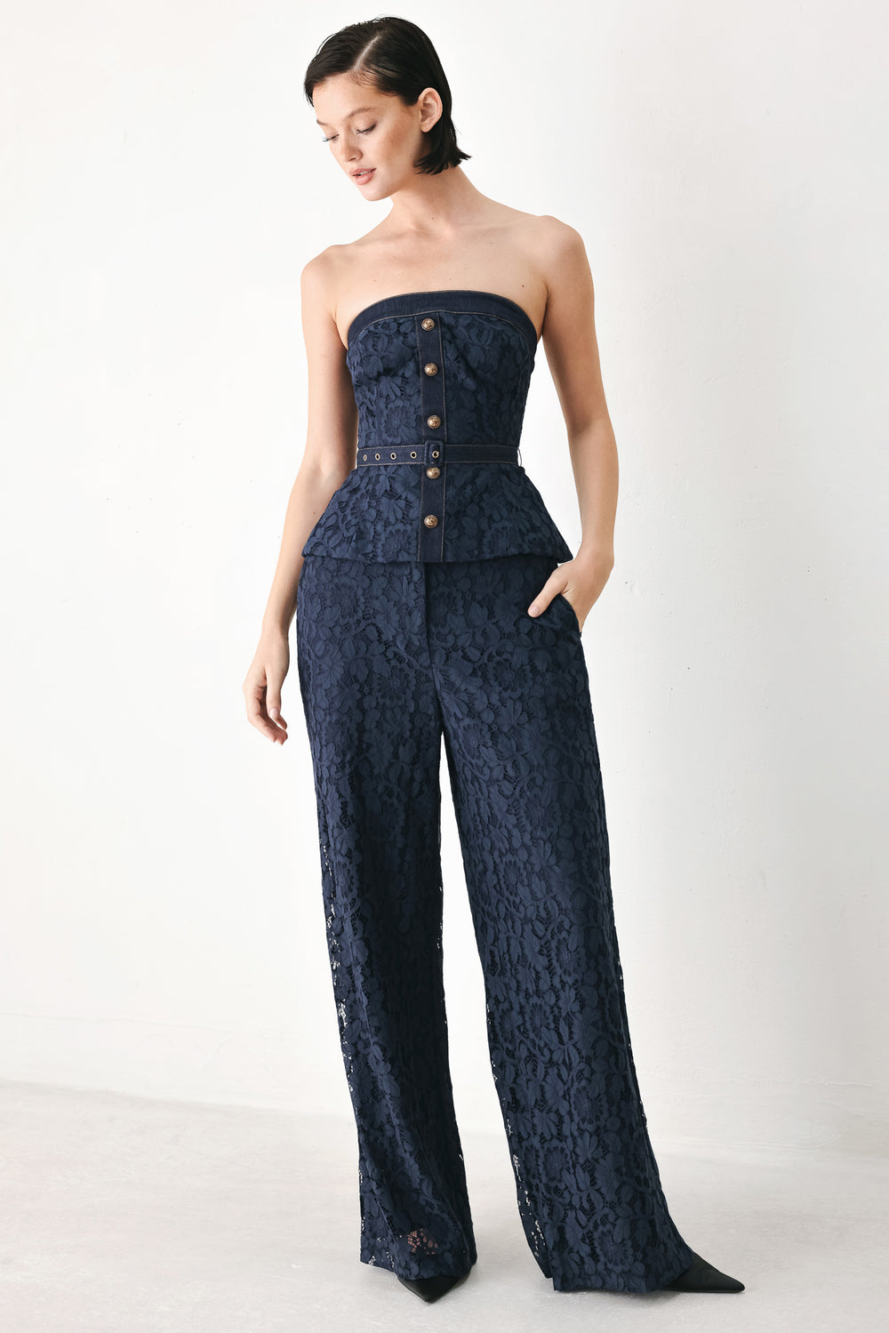 A woman wearing a strapless dark navy blue textured dress with a buttoned waist and a matching belt | FREEMARKET