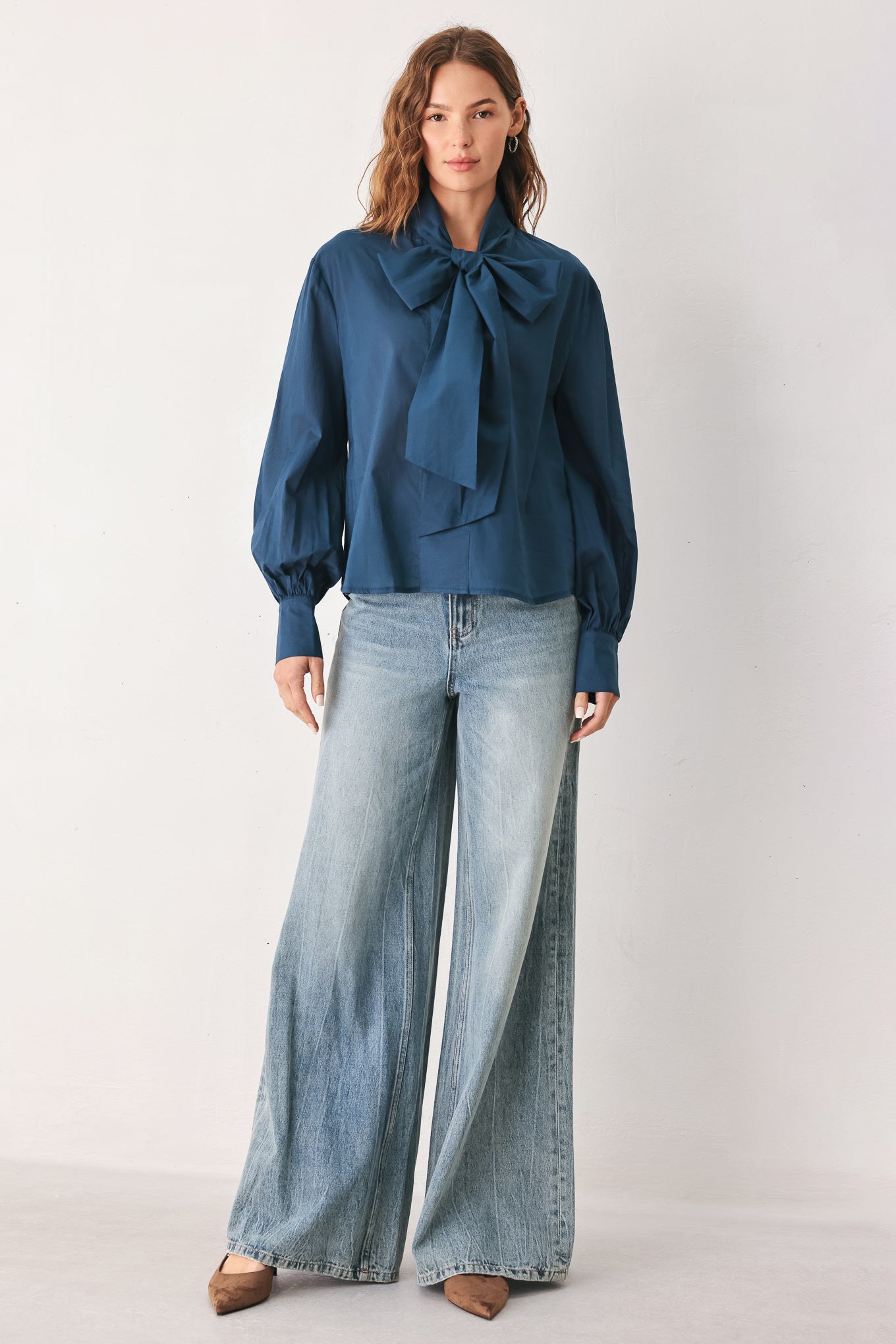 A woman wearing a dark navy blue long-sleeve blouse with a large bow at the collar | FREEMARKET