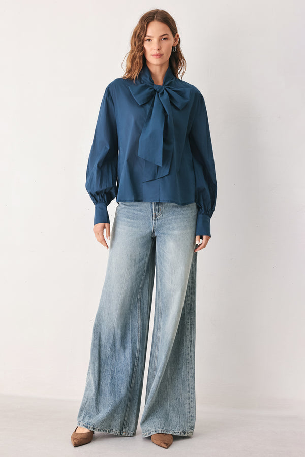 A woman wearing a dark navy blue long-sleeve blouse with a large bow at the collar | FREEMARKET