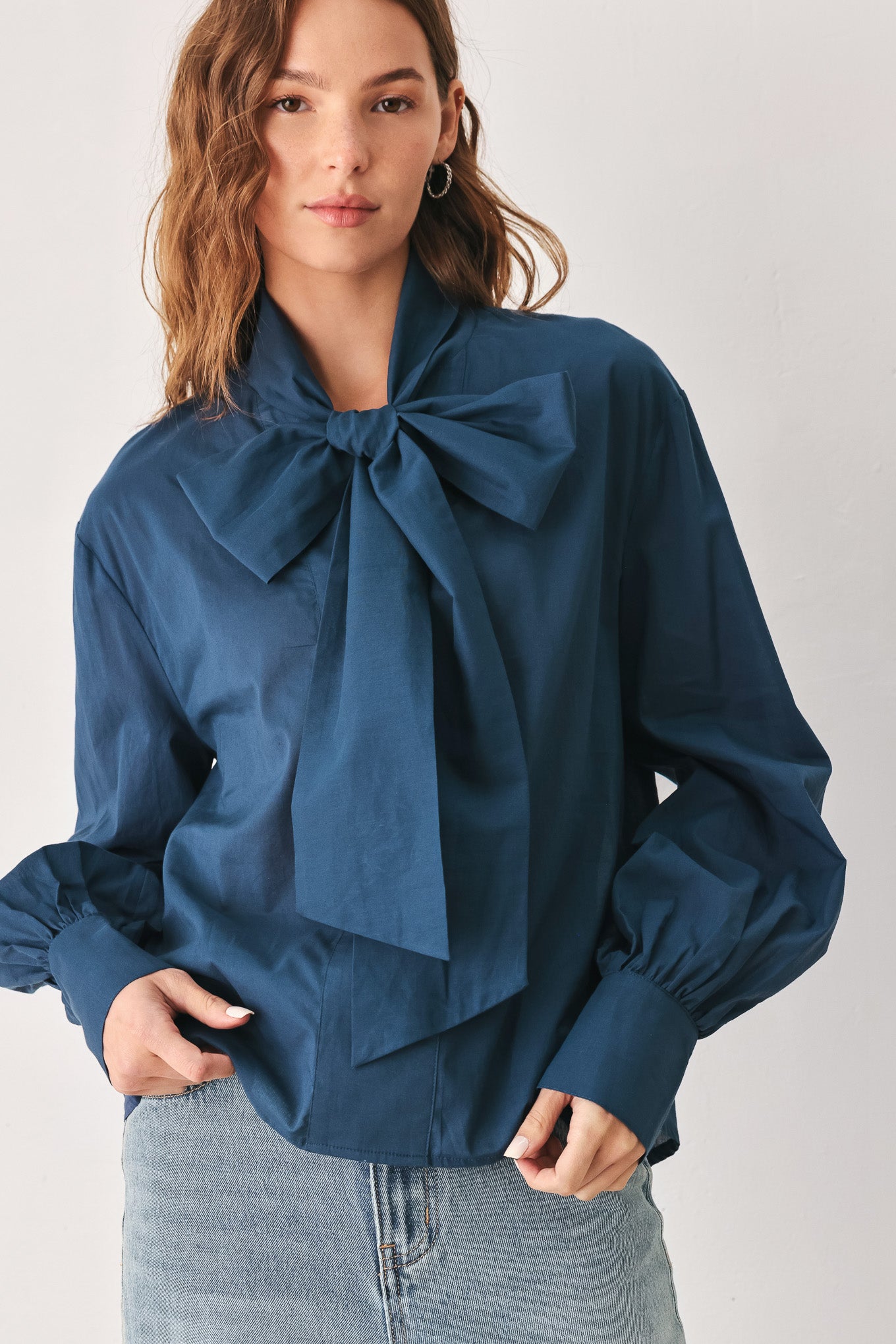 A woman wearing a dark navy blue long-sleeve blouse with a large bow at the collar | FREEMARKET