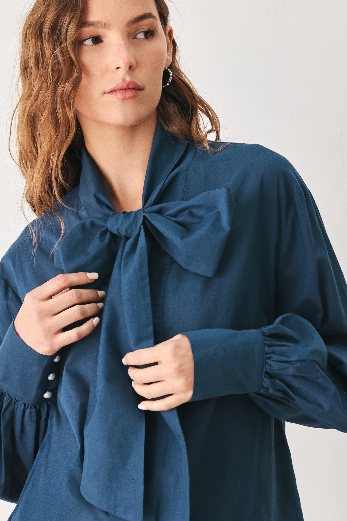 A woman wearing a dark navy blue long-sleeve blouse with a large bow at the collar | FREEMARKET