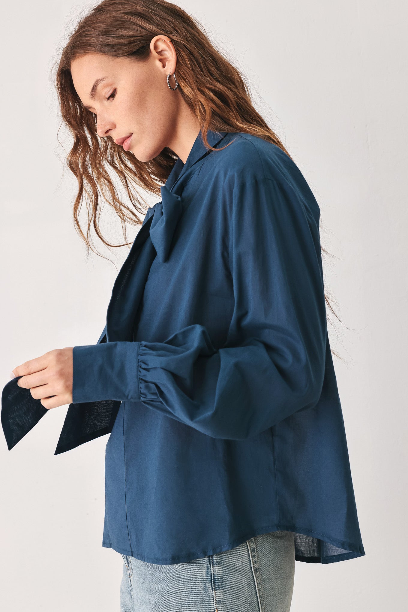A woman wearing a dark navy blue long-sleeve blouse with a large bow at the collar | FREEMARKET