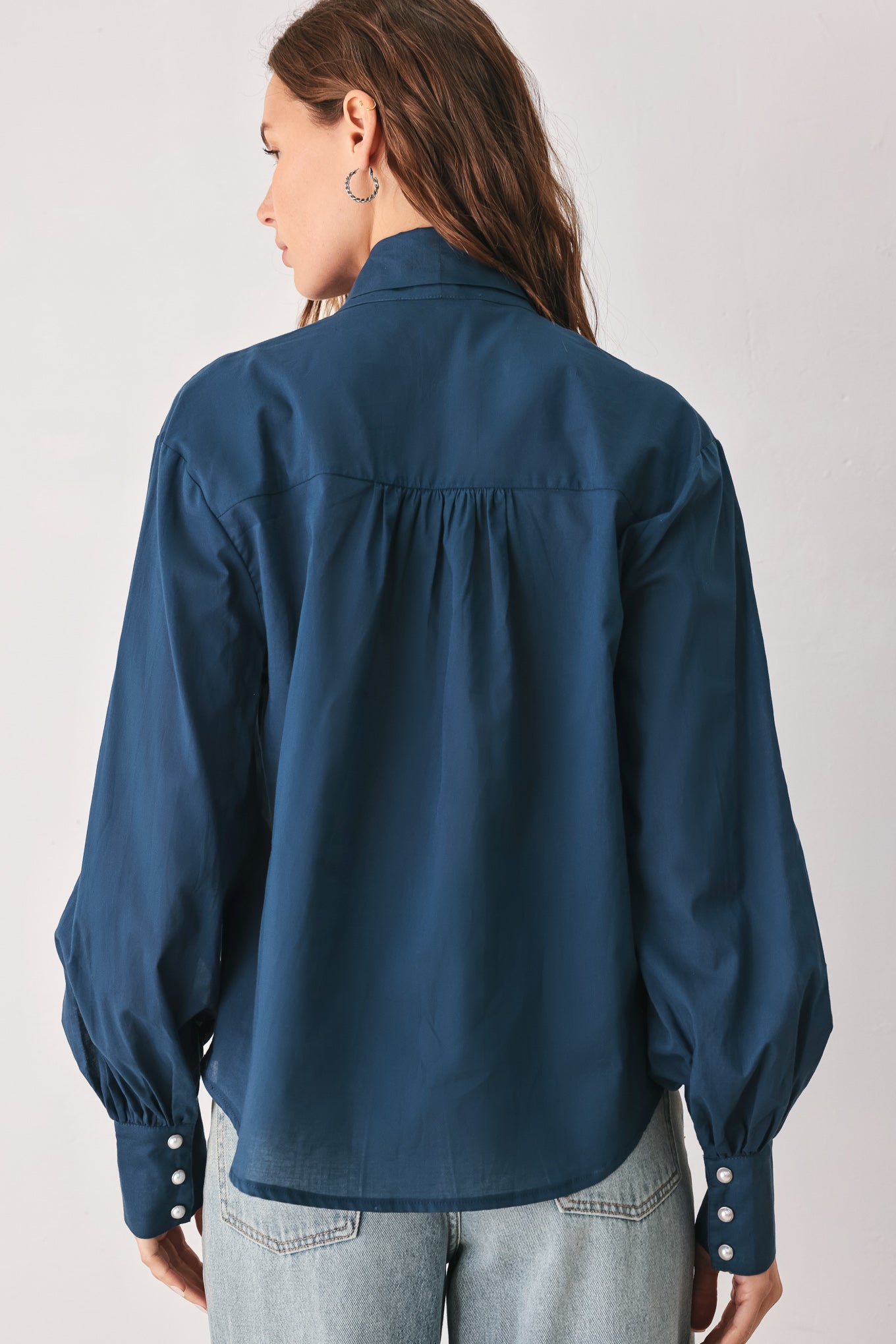 A woman wearing a dark navy blue long-sleeve blouse with a large bow at the collar | FREEMARKET