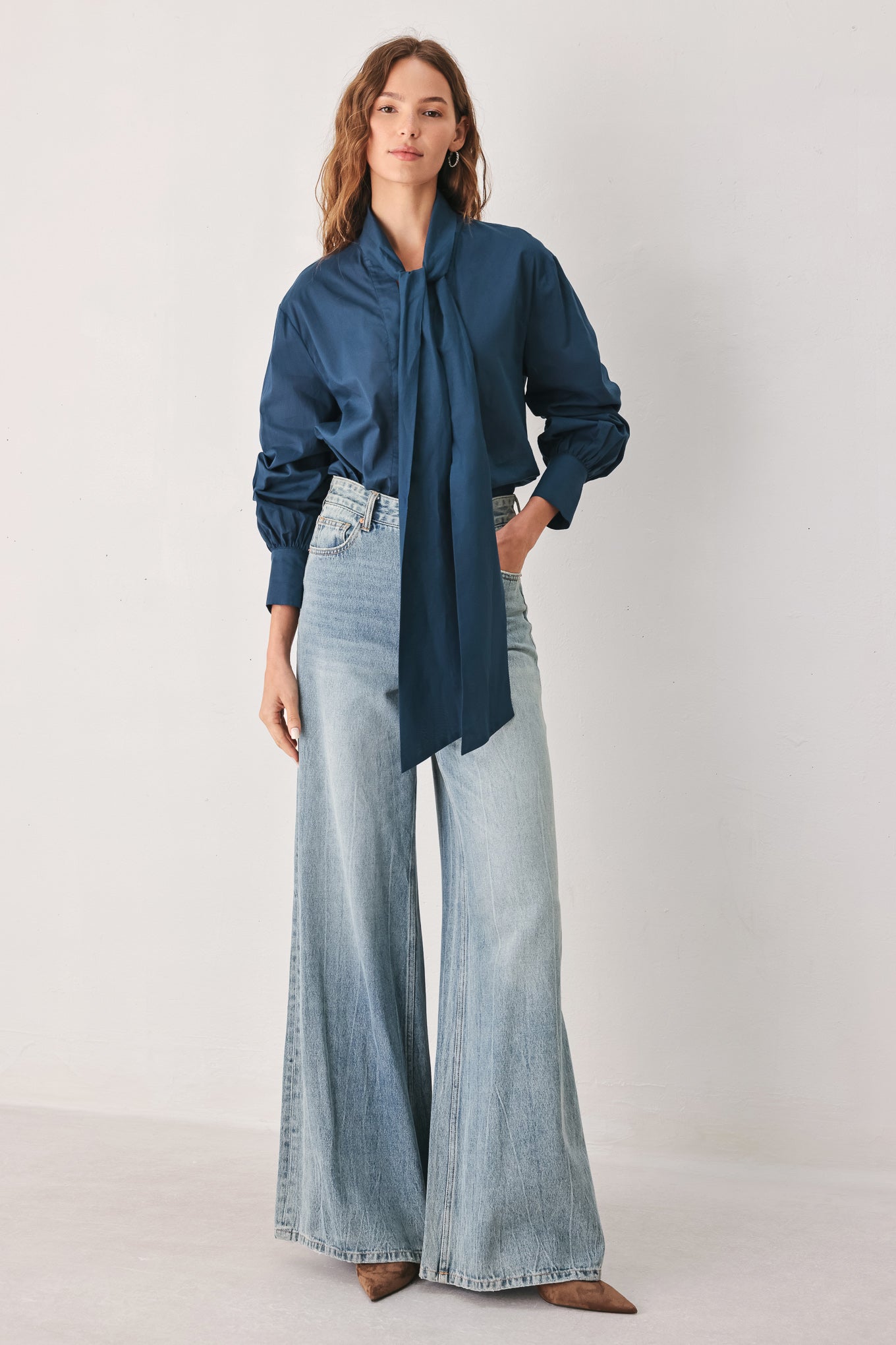 A woman wearing a dark navy blue long-sleeve blouse with a large bow at the collar | FREEMARKET