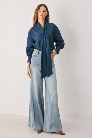 A woman wearing a dark navy blue long-sleeve blouse with a large bow at the collar | FREEMARKET
