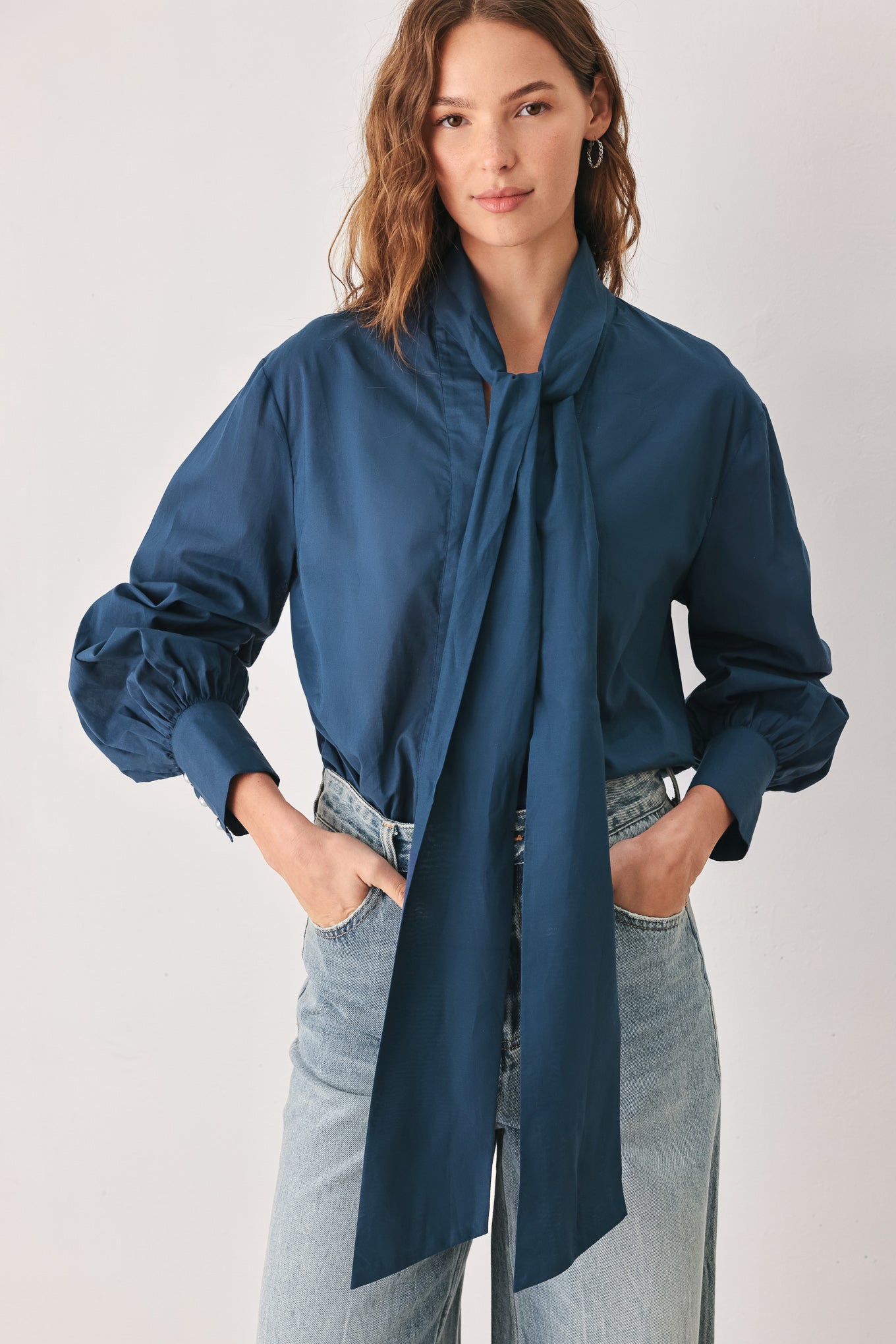 A woman wearing a dark navy blue long-sleeve blouse with a large bow at the collar | FREEMARKET