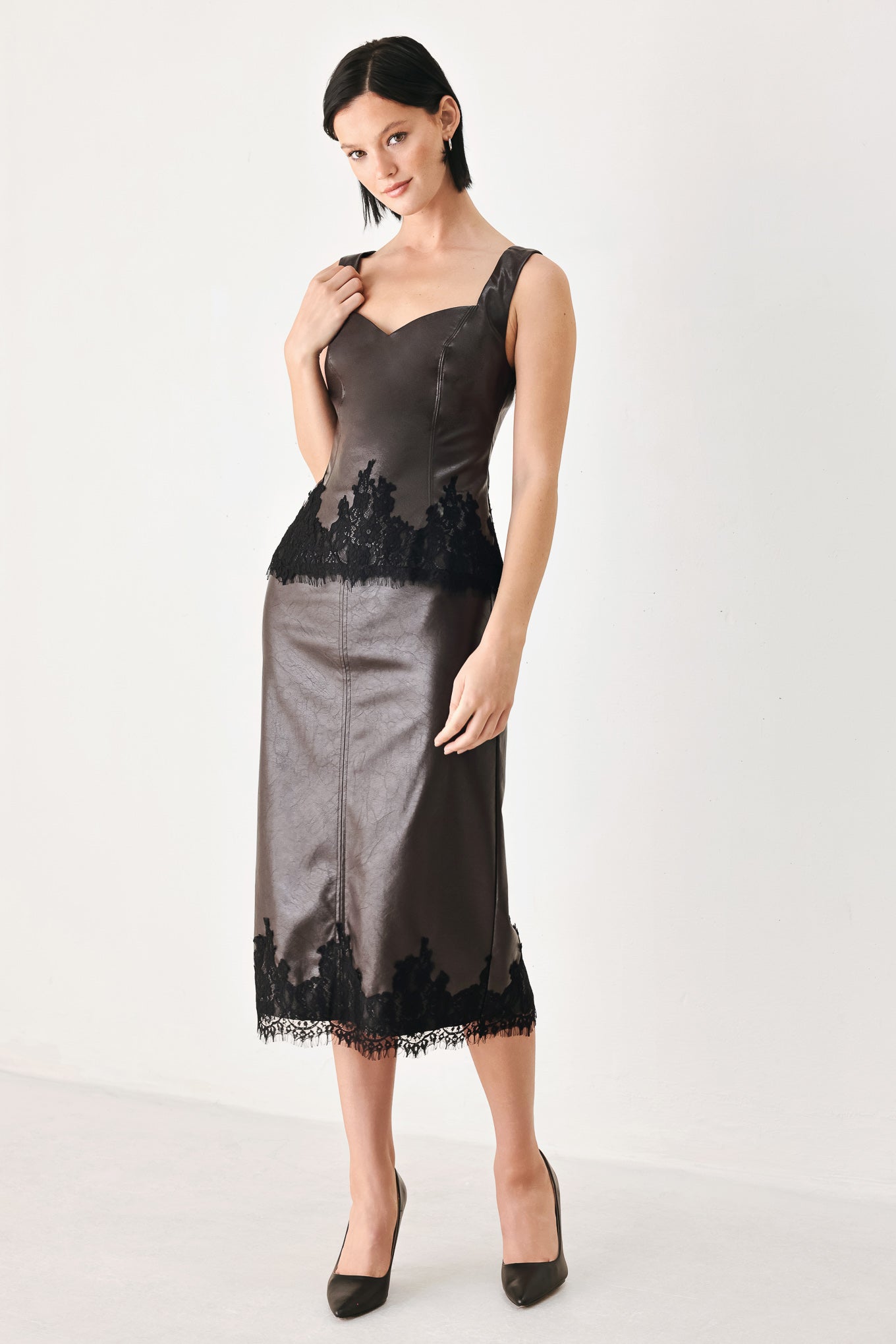 A model wearing a dark brown faux-leather corset top with a sweetheart neckline and black lace trim at the waist | FREEMARKET