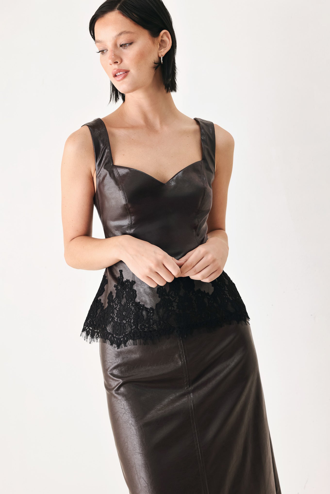 A model wearing a dark brown faux-leather corset top with a sweetheart neckline and black lace trim at the waist | FREEMARKET