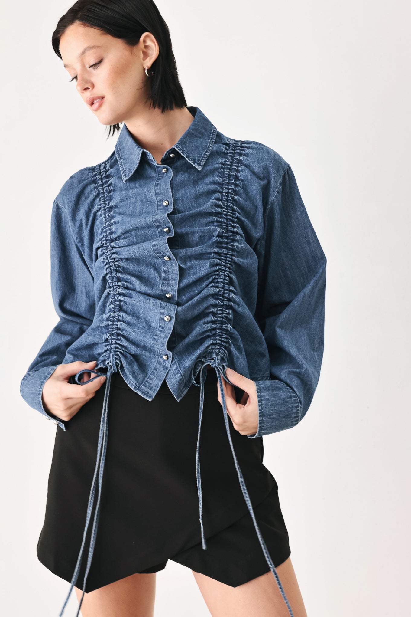 A model wearing a blue denim long-sleeve button-up shirt with ruched detailing | FREEMARKET