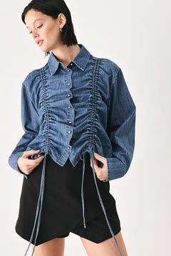 A model wearing a blue denim long-sleeve button-up shirt with ruched detailing | FREEMARKET