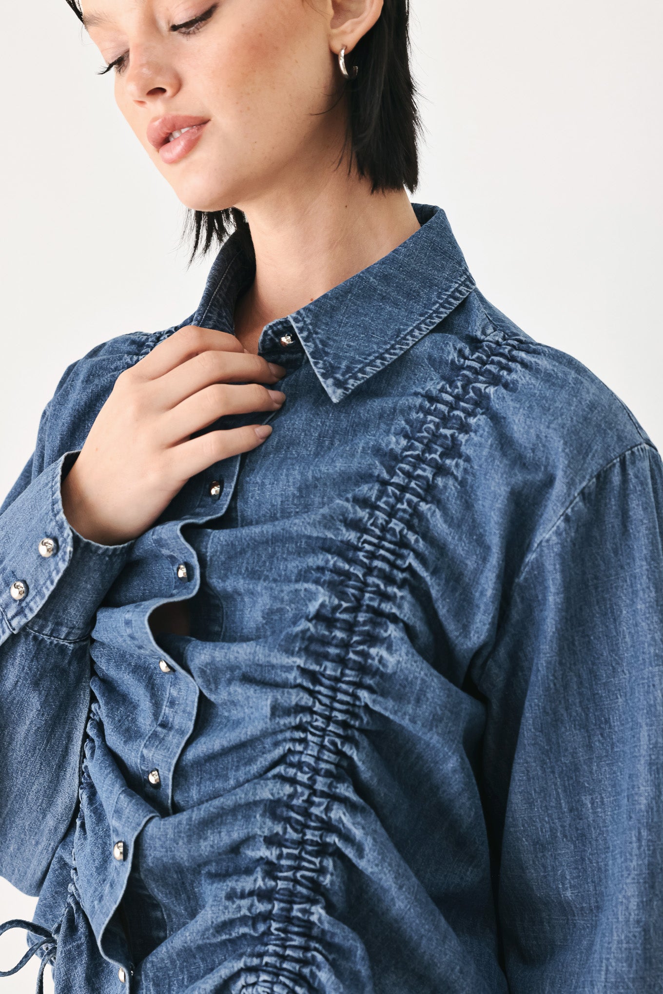 A model wearing a blue denim long-sleeve button-up shirt with ruched detailing | FREEMARKET