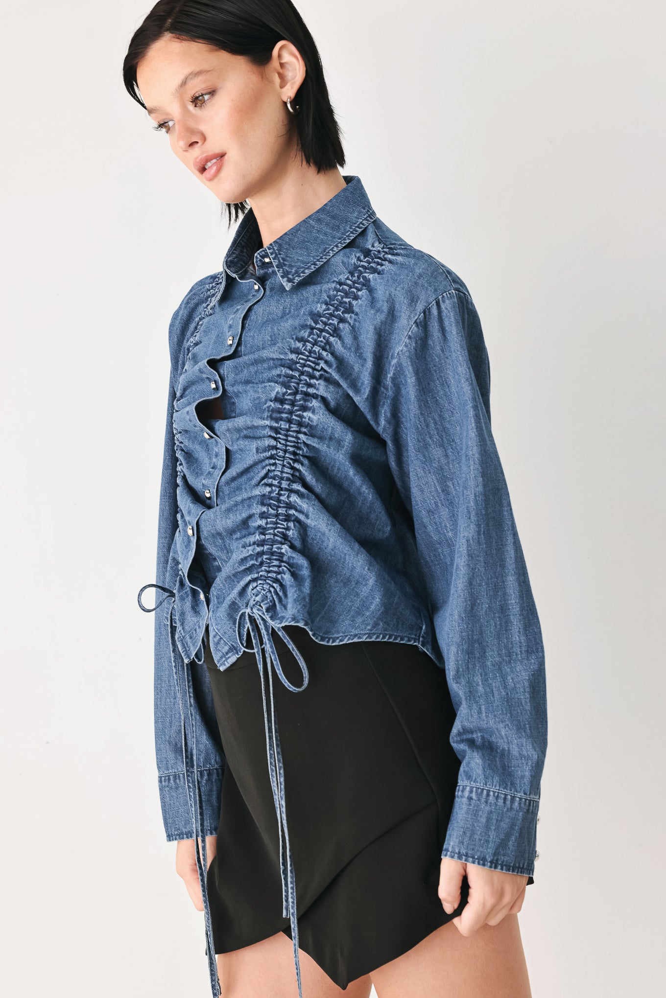 A model wearing a blue denim long-sleeve button-up shirt with ruched detailing | FREEMARKET