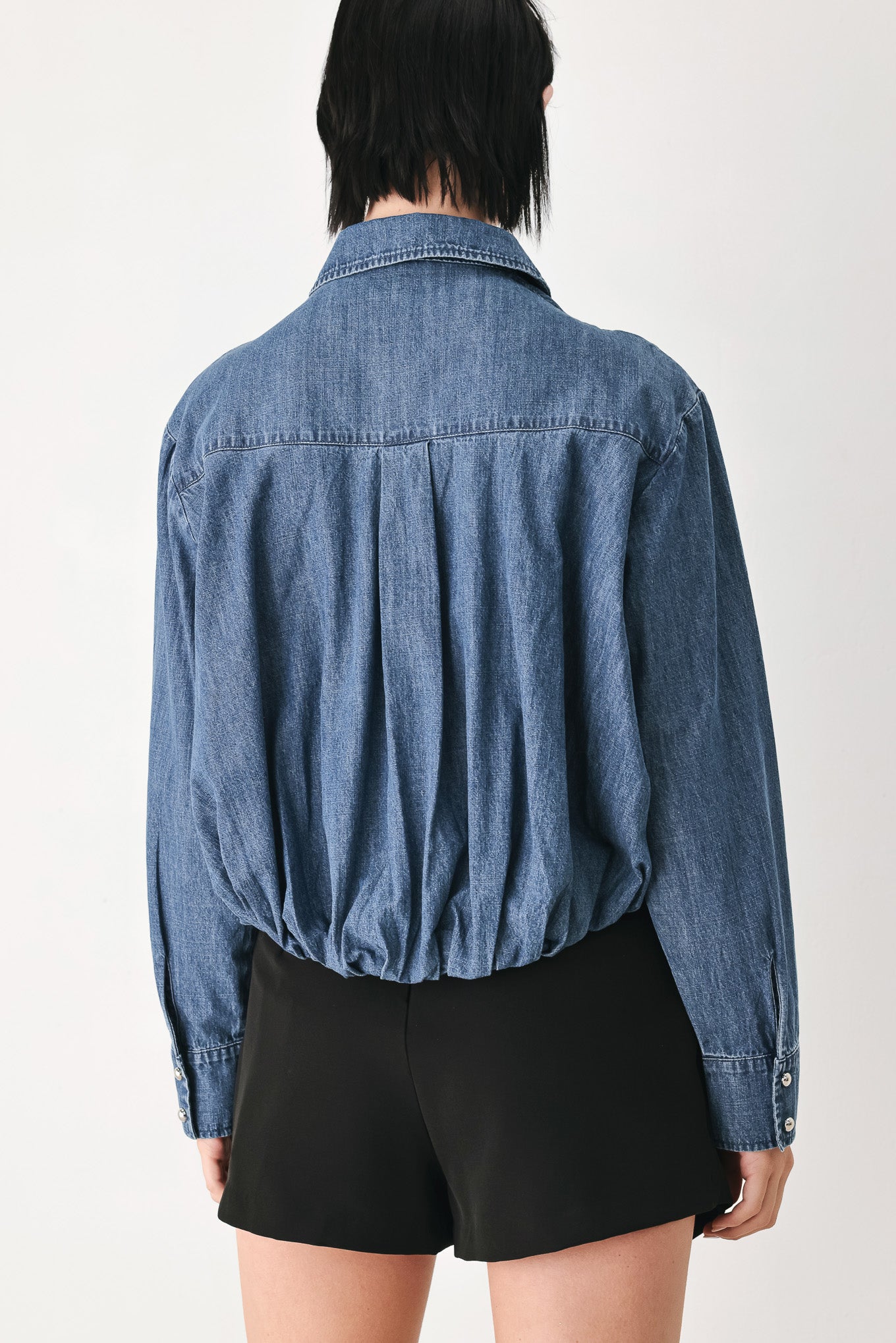 A model wearing a blue denim long-sleeve button-up shirt with ruched detailing | FREEMARKET