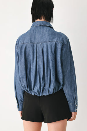 A model wearing a blue denim long-sleeve button-up shirt with ruched detailing | FREEMARKET