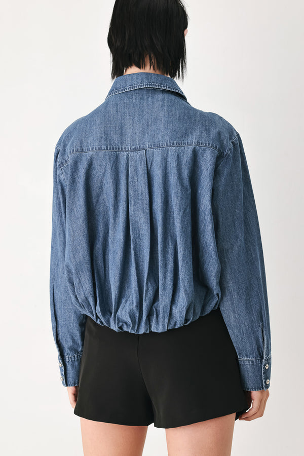 A model wearing a blue denim long-sleeve button-up shirt with ruched detailing | FREEMARKET