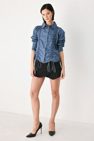 A model wearing a blue denim long-sleeve button-up shirt with ruched detailing | FREEMARKET