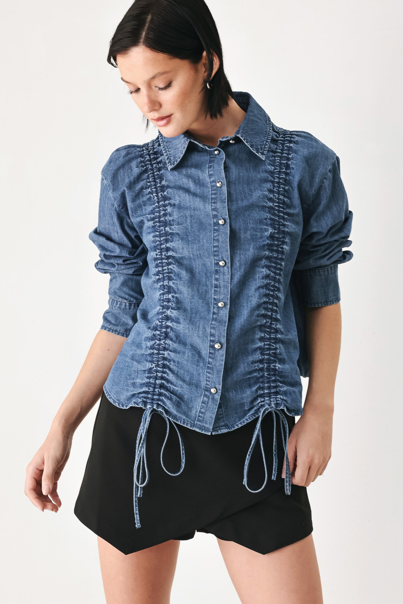 A model wearing a blue denim long-sleeve button-up shirt with ruched detailing | FREEMARKET