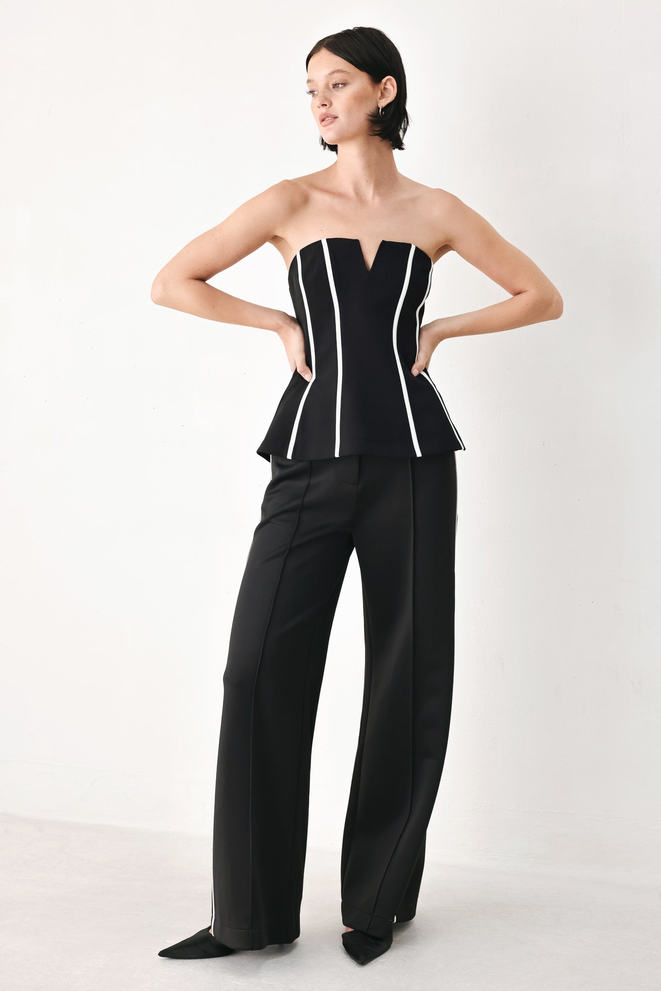 A woman wearing a strapless black corset-style top with bold white vertical stripes | FREEMARKET