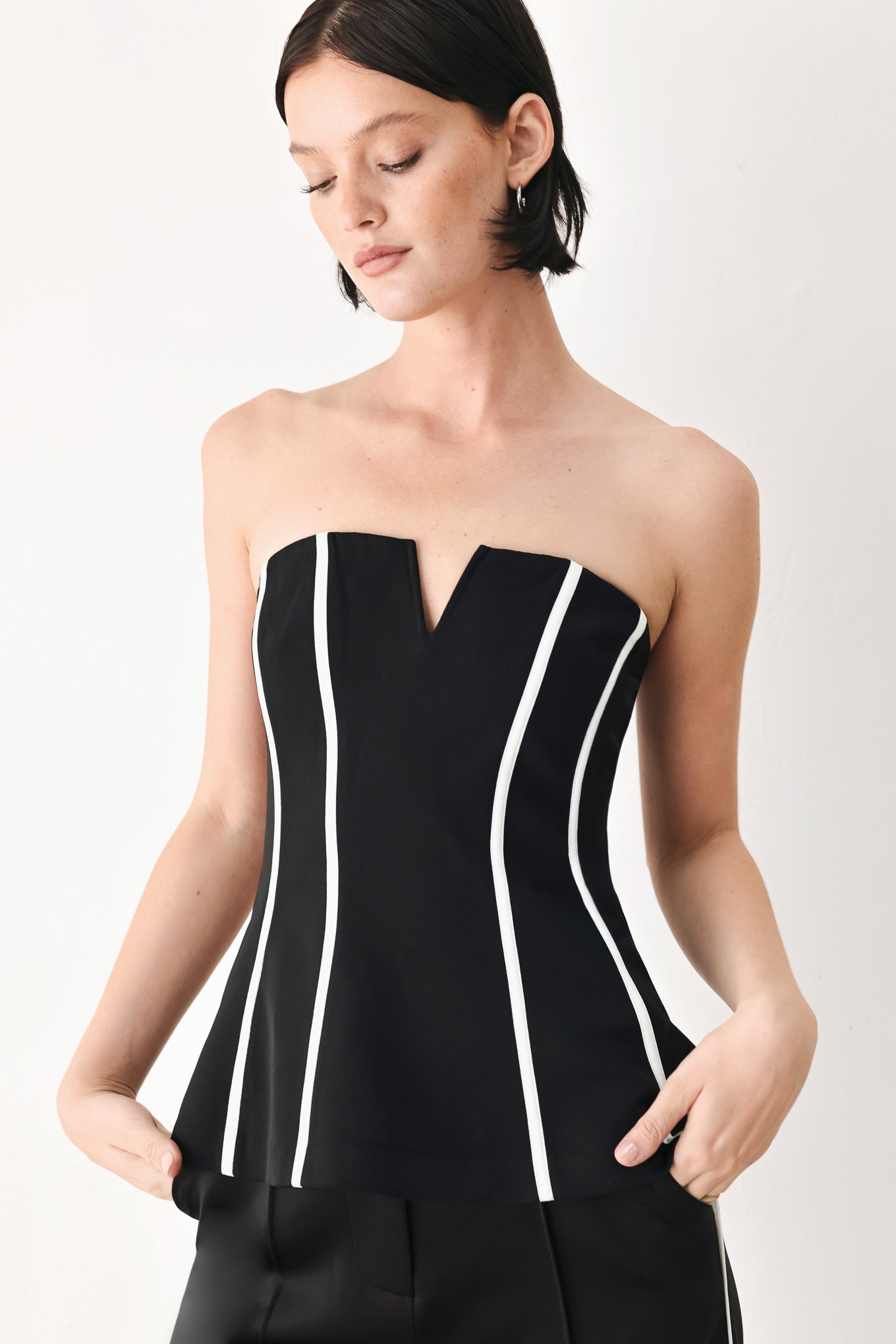 A woman wearing a strapless black corset-style top with bold white vertical stripes | FREEMARKET