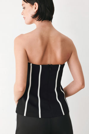 A woman wearing a strapless black corset-style top with bold white vertical stripes | FREEMARKET