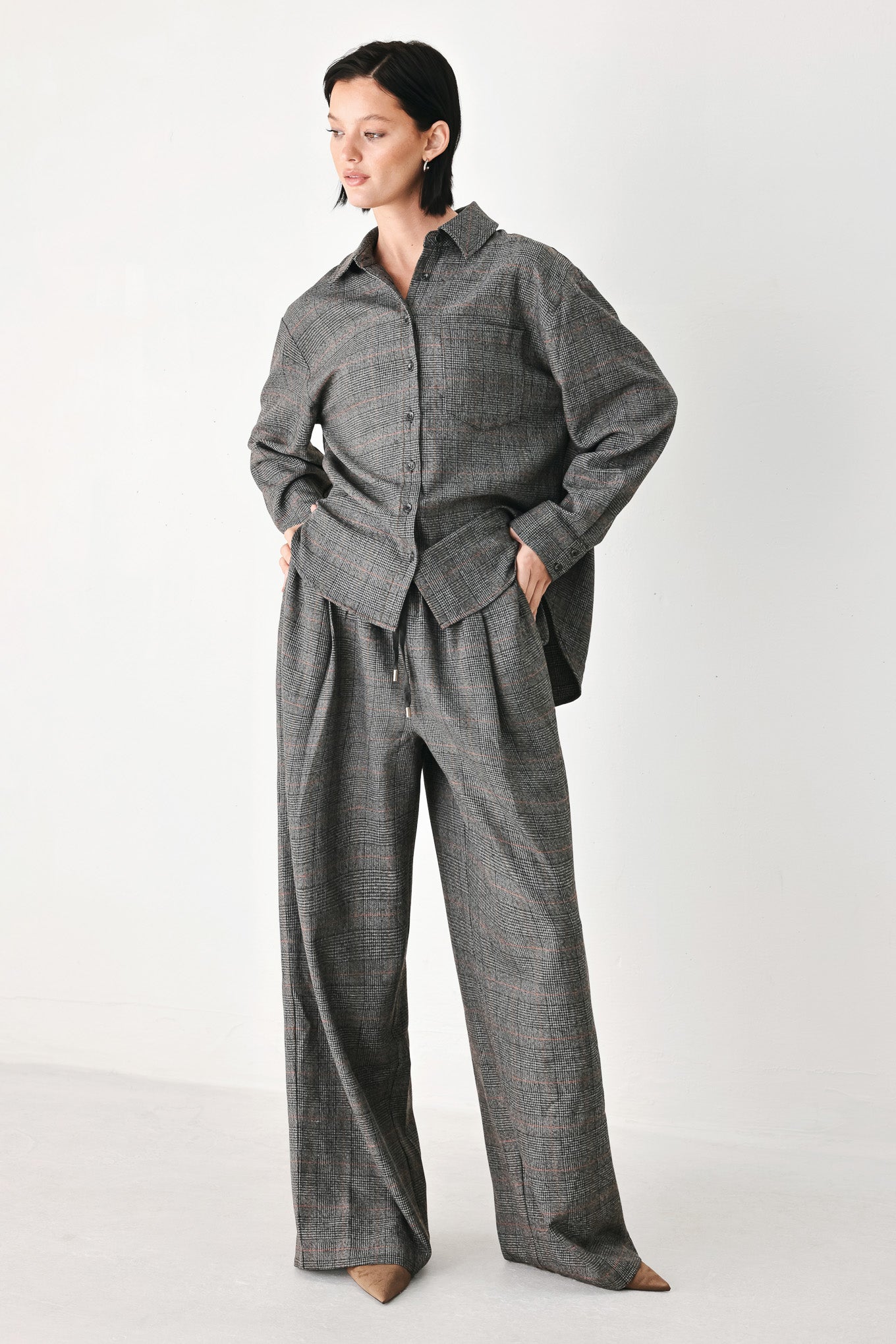 A model wearing a dark gray oversized button-up shirt with a subtle brown and orange windowpane plaid pattern | FREEMARKET