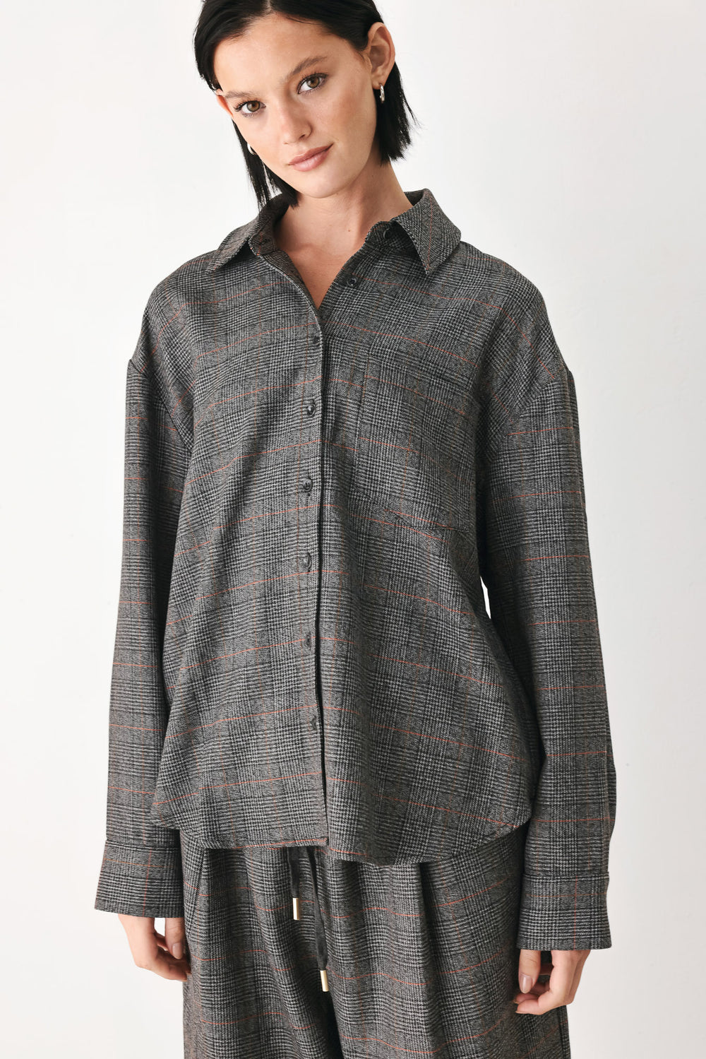 A model wearing a dark gray oversized button-up shirt with a subtle brown and orange windowpane plaid pattern | FREEMARKET