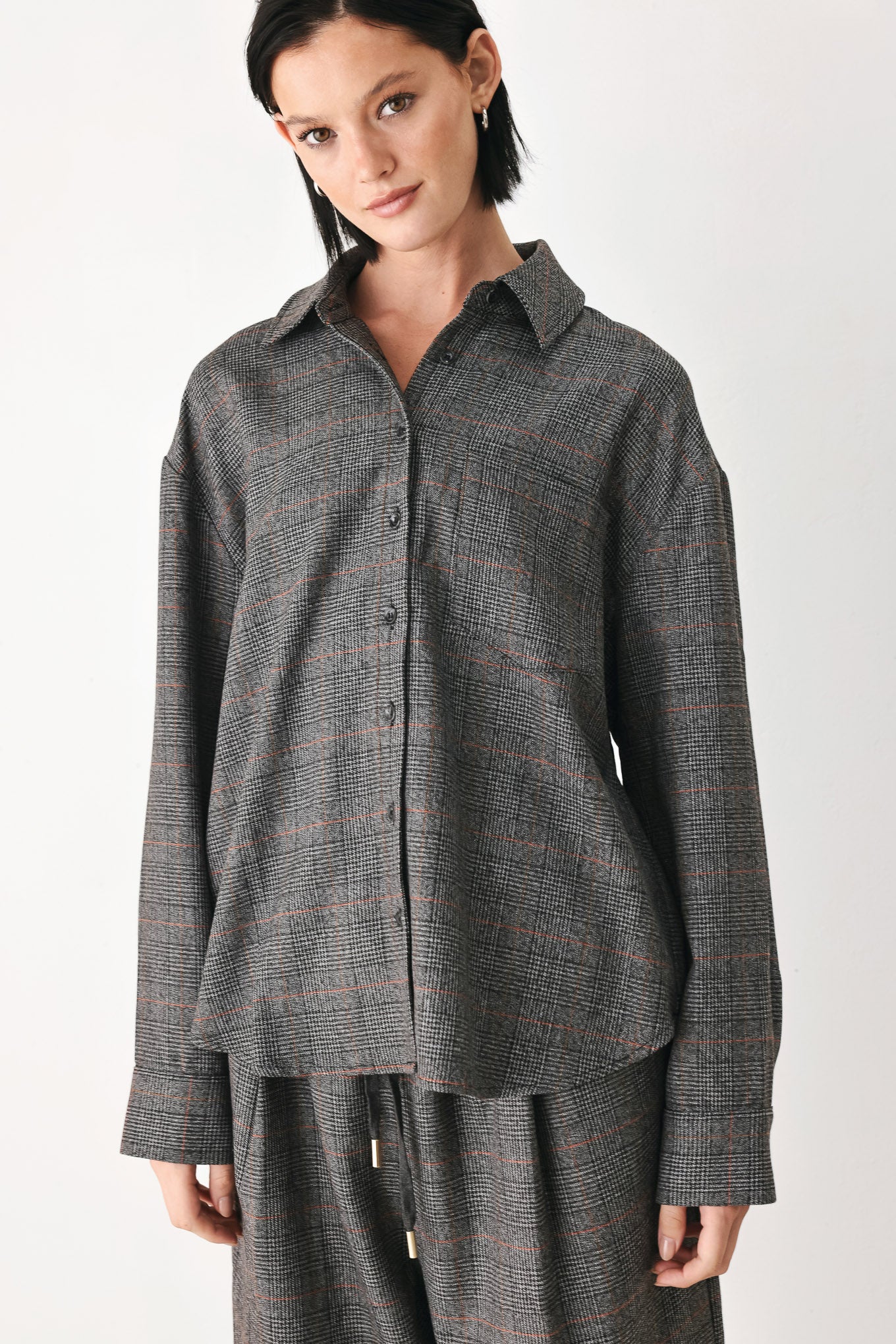 A model wearing a dark gray oversized button-up shirt with a subtle brown and orange windowpane plaid pattern | FREEMARKET