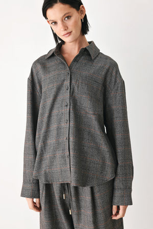 A model wearing a dark gray oversized button-up shirt with a subtle brown and orange windowpane plaid pattern | FREEMARKET