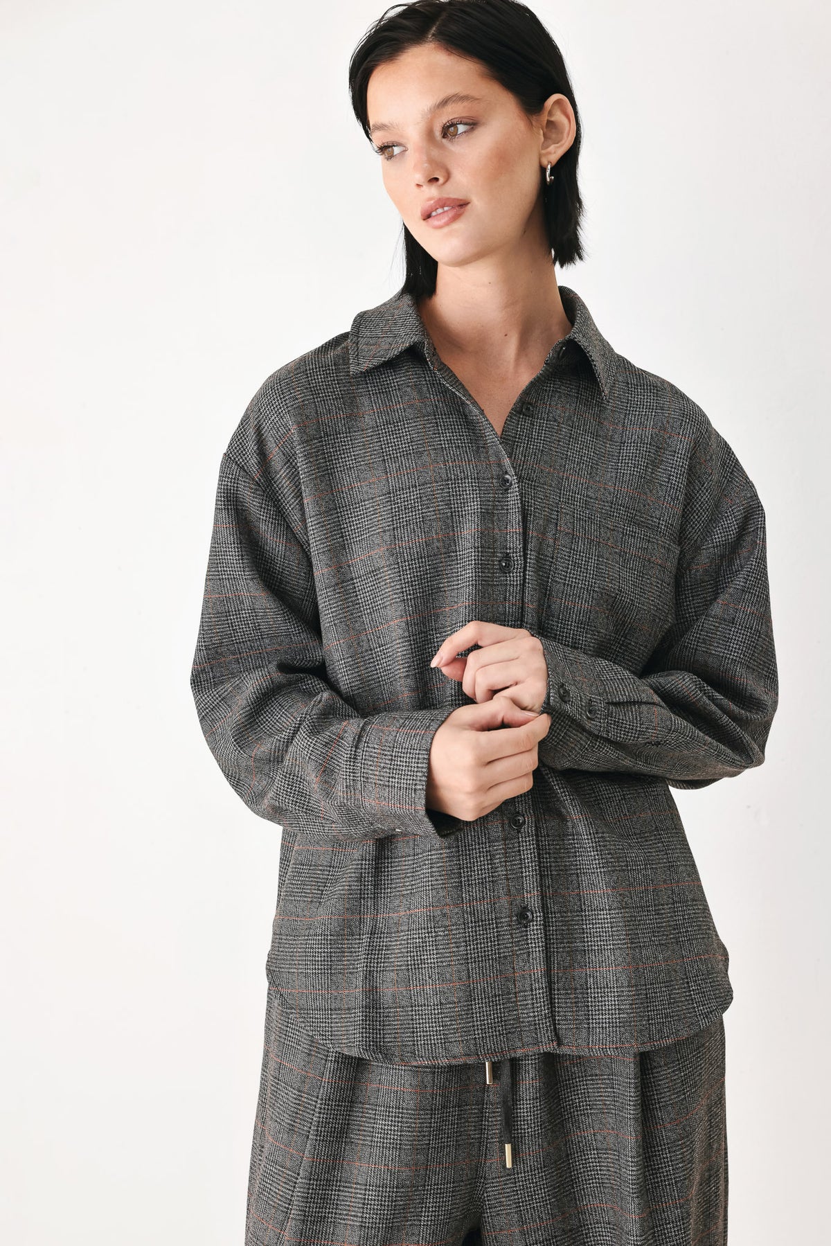 A model wearing a dark gray oversized button-up shirt with a subtle brown and orange windowpane plaid pattern | FREEMARKET