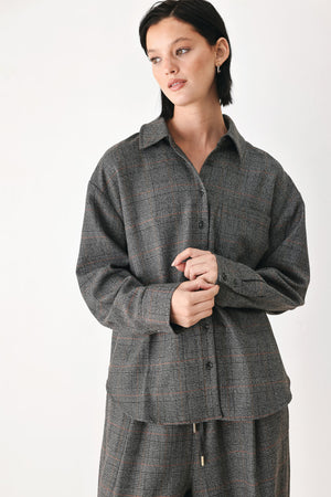 A model wearing a dark gray oversized button-up shirt with a subtle brown and orange windowpane plaid pattern | FREEMARKET